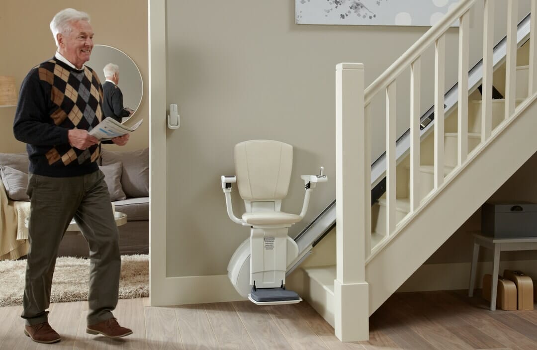 homeglide extra stairlift ready to use at bottom of stairs man walking past