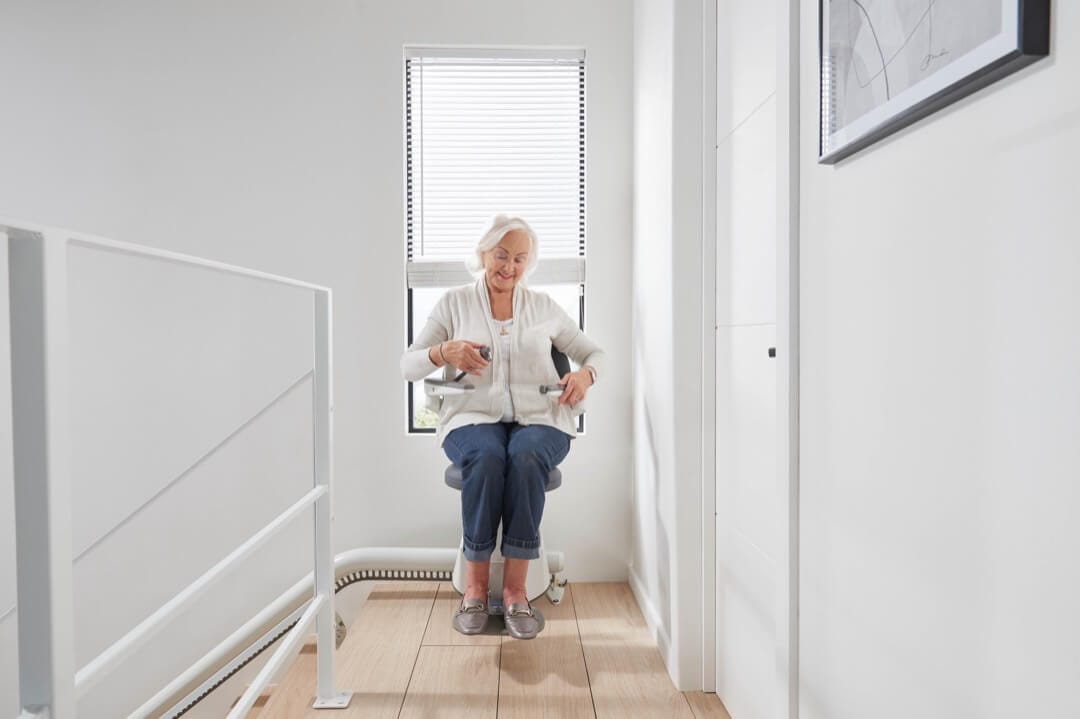 Flow X Stairlift fastening seatbelt at top of stairs